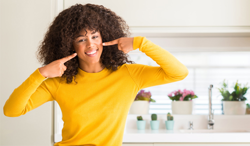 young woman pointing to her smile